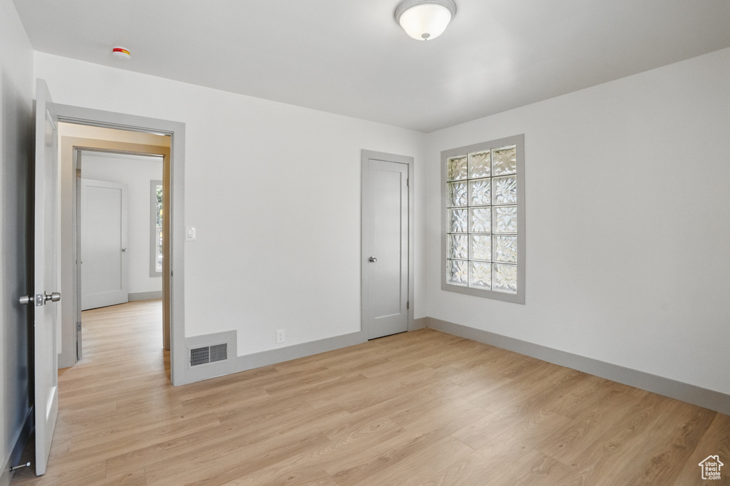Spare room featuring light wood-style flooring, baseboards, and a smoke detector