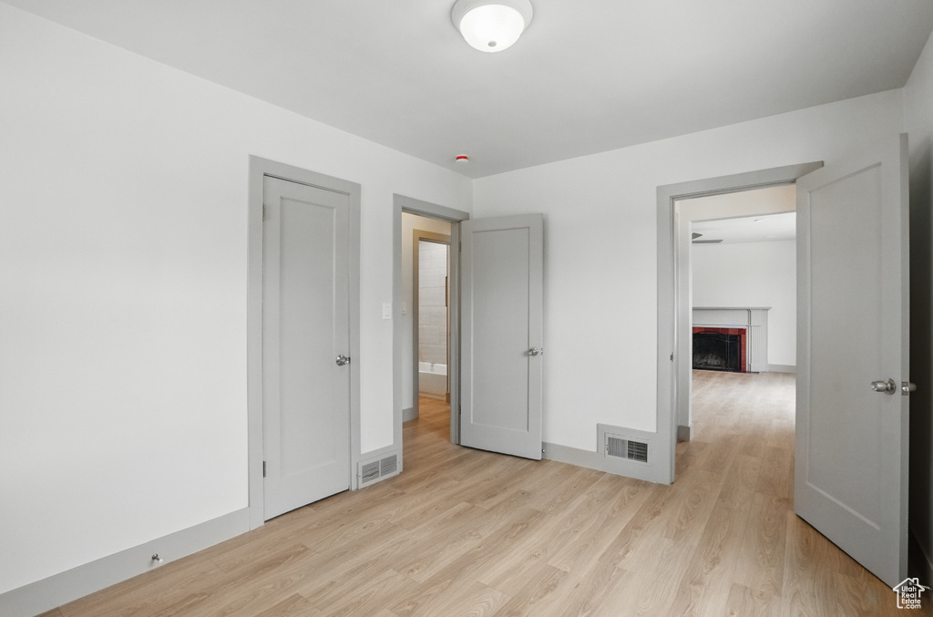Unfurnished bedroom with light wood-type flooring, a fireplace, and baseboards