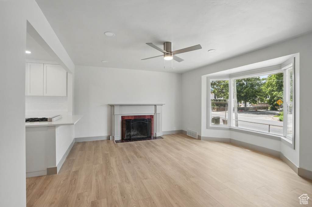 Unfurnished living room featuring light wood-style floors, a ceiling fan, a fireplace with flush hearth, baseboards, and recessed lighting