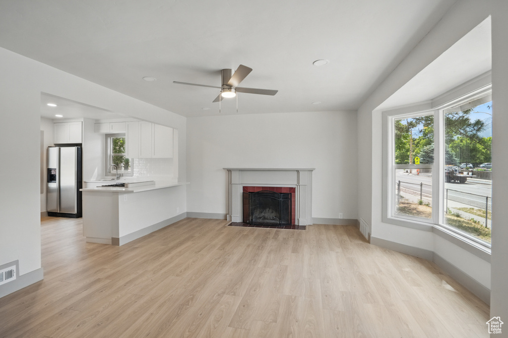 Unfurnished living room with a sink, plenty of natural light, light wood-type flooring, and recessed lighting