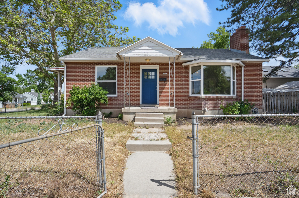 View of front of home featuring a chimney, a gate, a fenced front yard, and brick siding