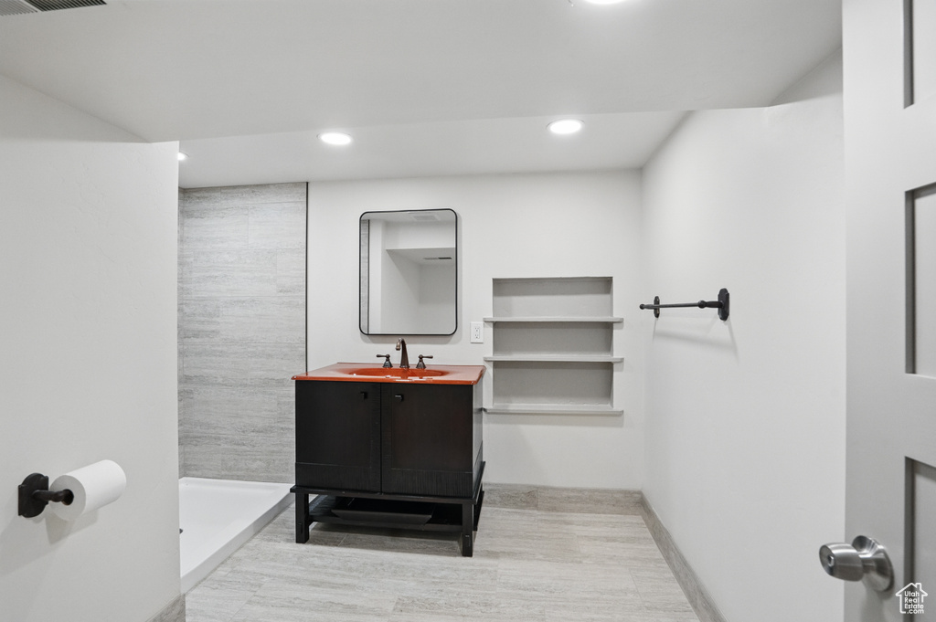 Full bath with tiled shower, recessed lighting, vanity, and wood finished floors