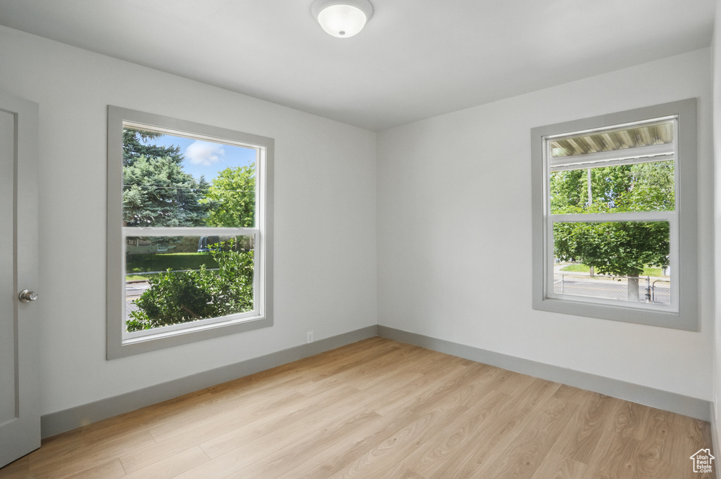 Unfurnished room featuring healthy amount of natural light, light wood-type flooring, and baseboards