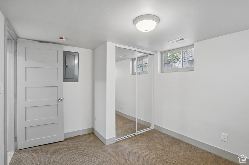Unfurnished bedroom featuring electric panel, carpet floors, a closet, and baseboards
