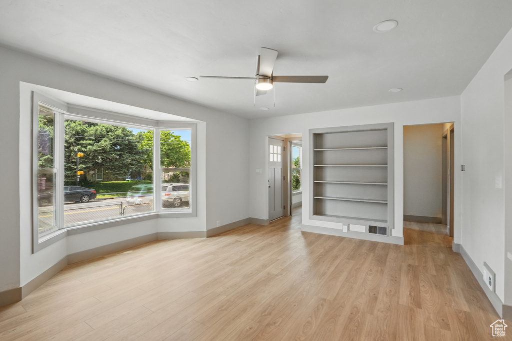 Spare room with ceiling fan, baseboards, built in features, and plenty of natural light