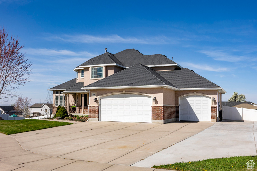 View of front of property featuring driveway, an attached garage, stucco siding, brick siding, and a shingled roof