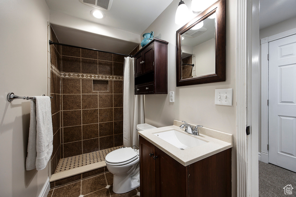 Full bath with a tile shower, vanity, and tile patterned flooring