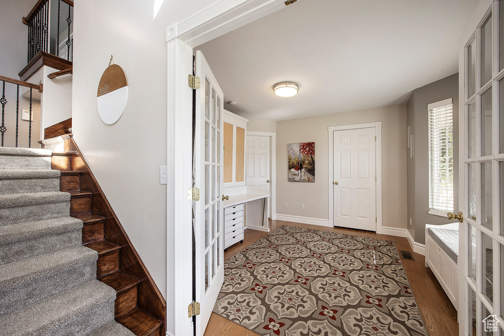 Staircase featuring wood finished floors and french doors