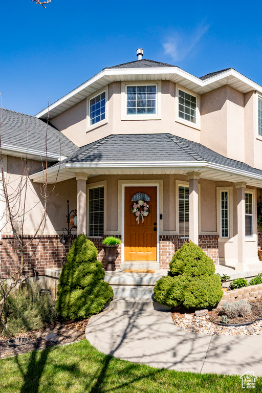 View of front of home with stucco siding, a porch, and brick siding