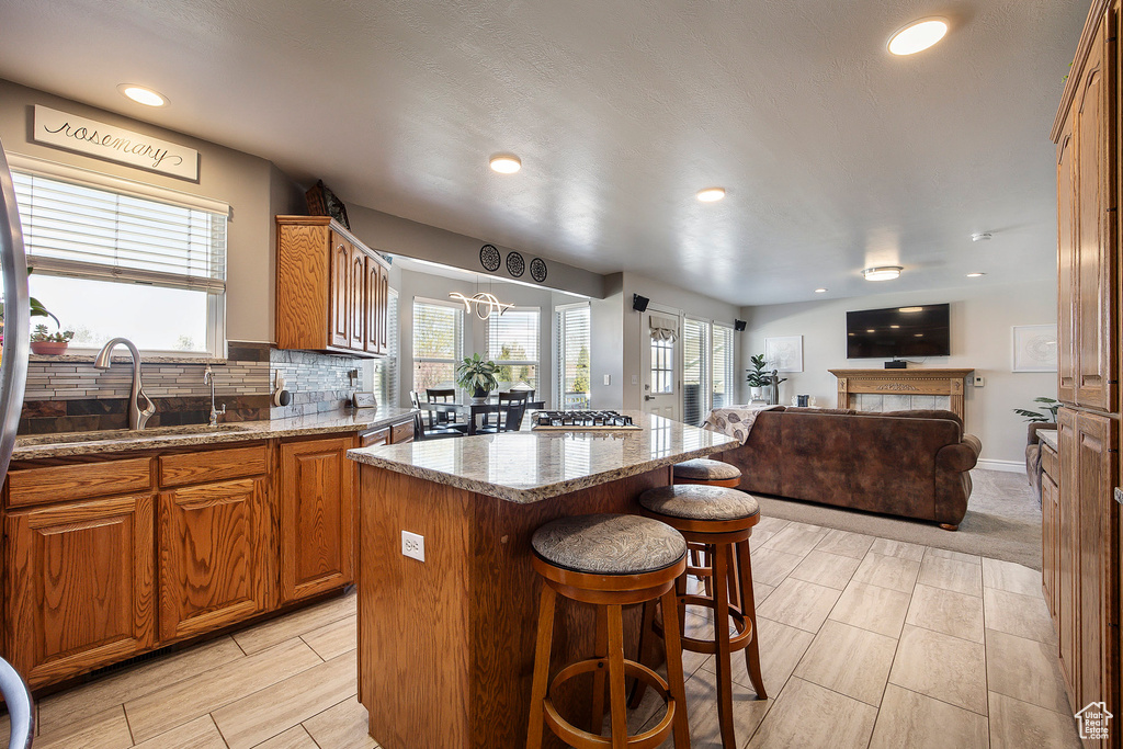Kitchen with a center island, a breakfast bar, brown cabinets, open floor plan, and light stone countertops