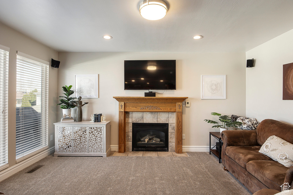 Living area with carpet flooring, a tiled fireplace, and recessed lighting