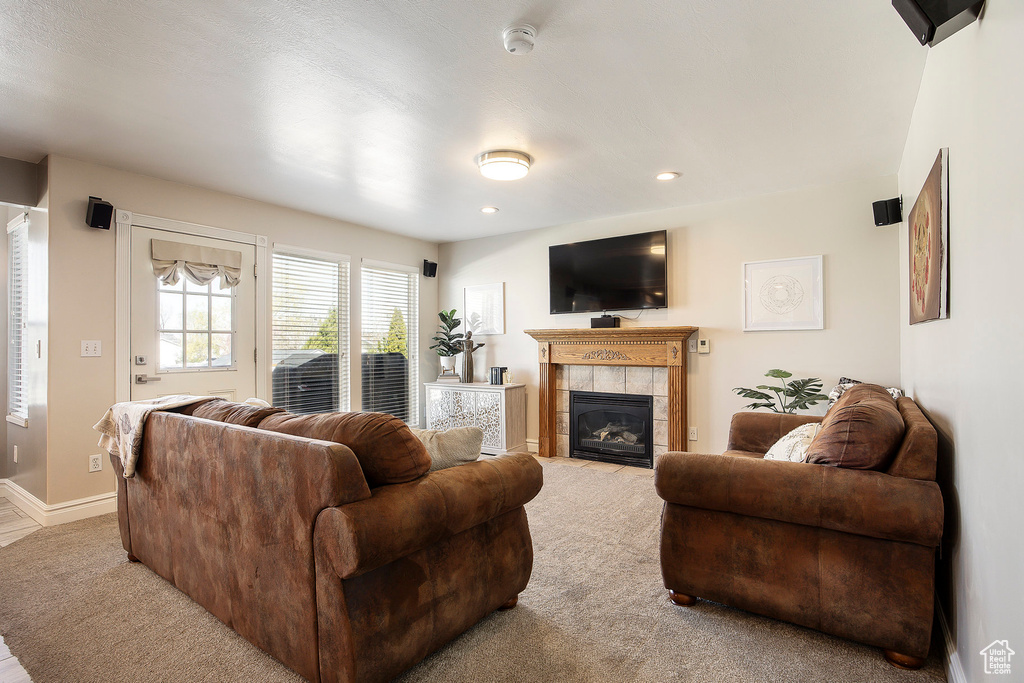 Living room with carpet flooring, a tile fireplace, and recessed lighting