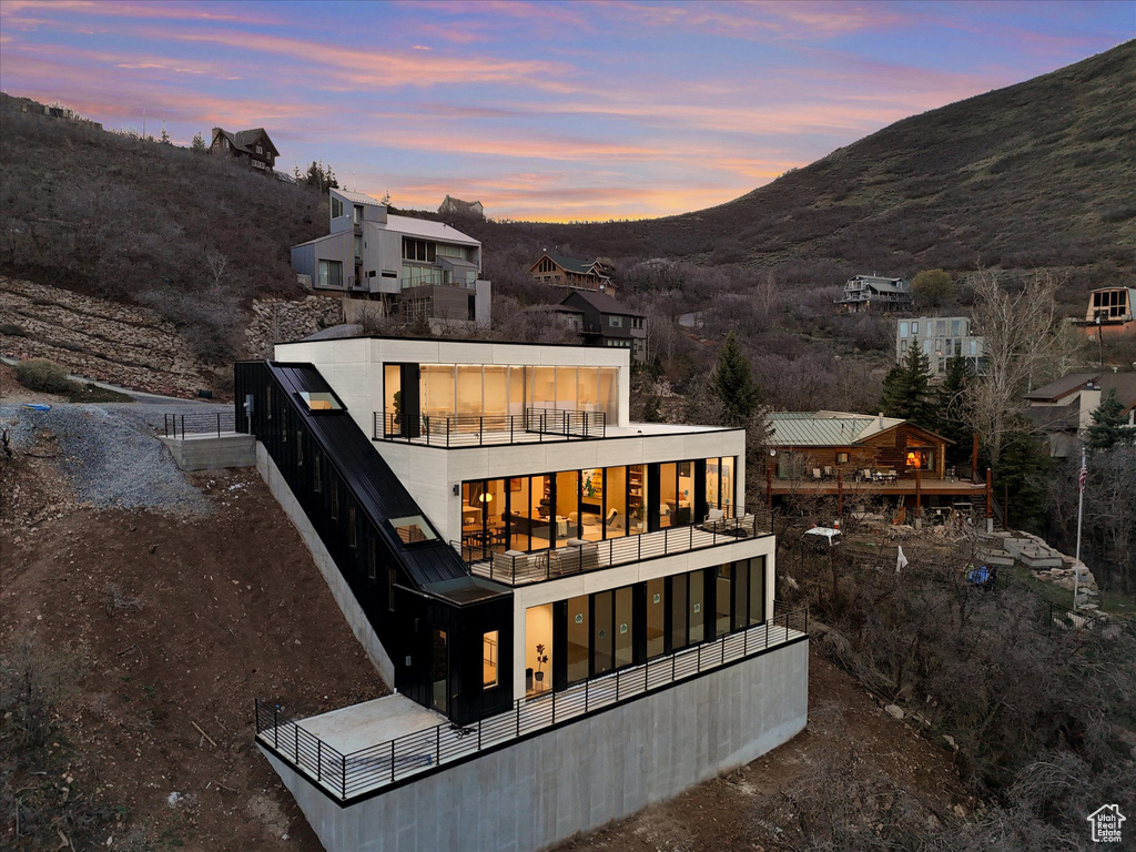 Back of property at dusk featuring a balcony and a mountain view