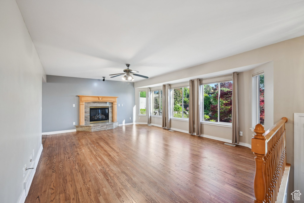 Unfurnished living room with ceiling fan, light wood-type flooring, a glass covered fireplace, and baseboards