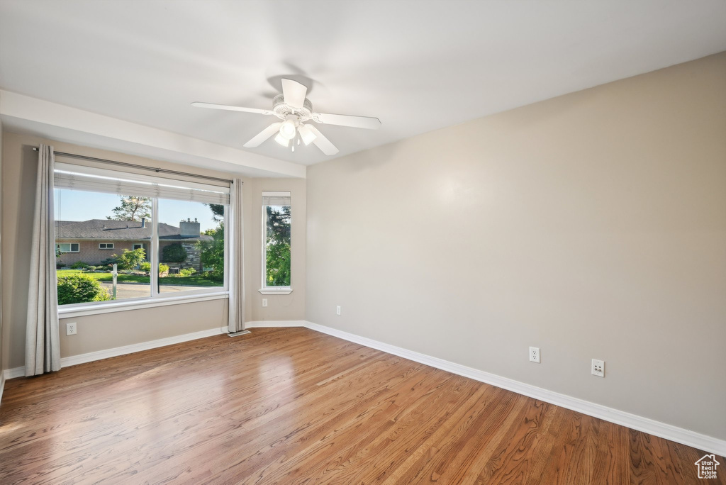 Spare room featuring healthy amount of natural light, baseboards, light wood-style floors, and ceiling fan