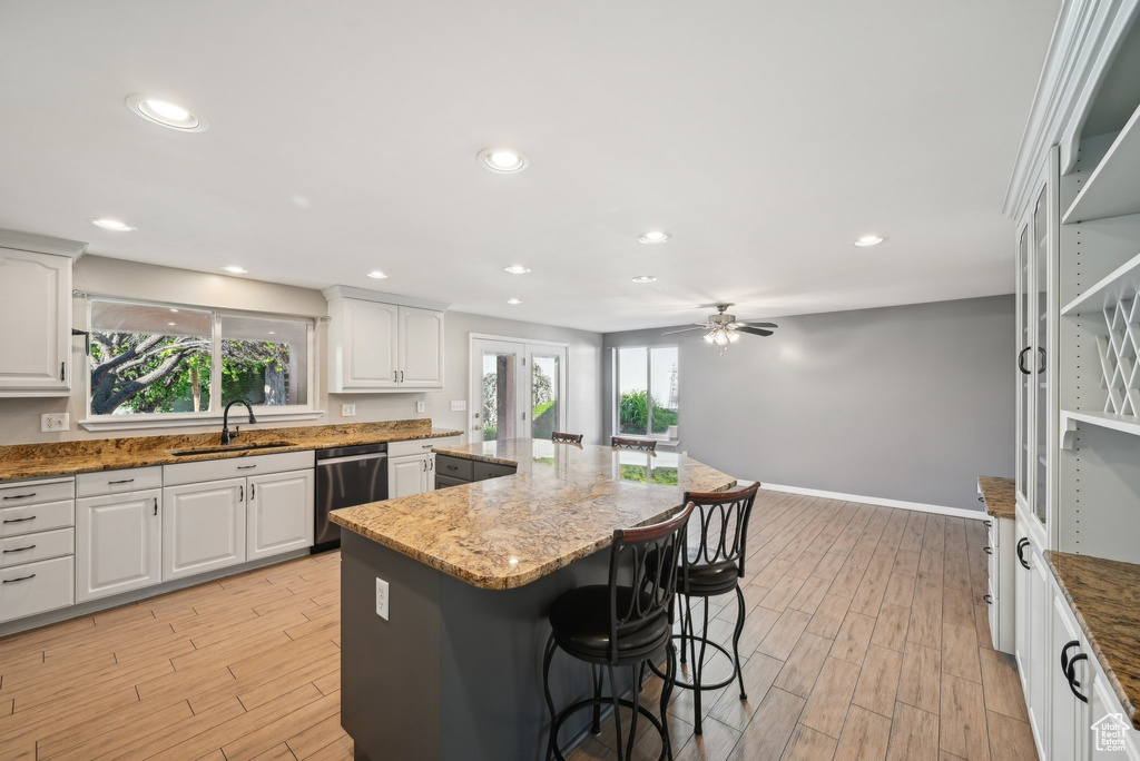 Kitchen with dishwasher, a sink, a center island, a kitchen breakfast bar, and light wood-style flooring