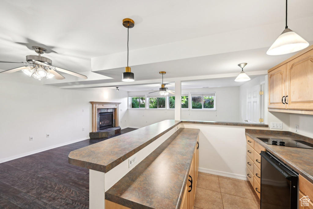 Kitchen with a ceiling fan, dark countertops, light brown cabinets, and black appliances