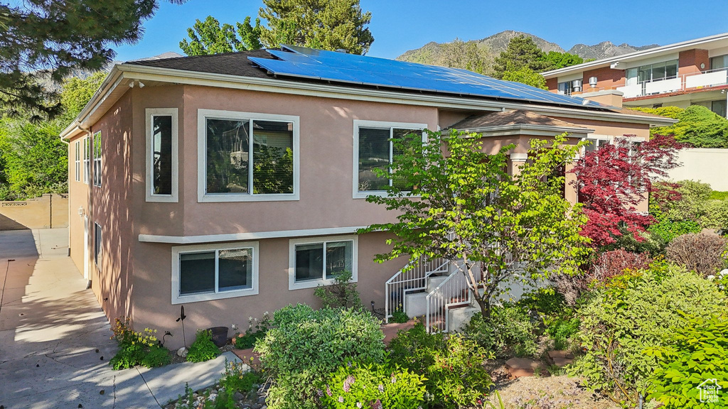 Rear view of property with stucco siding, solar panels, and a mountain view