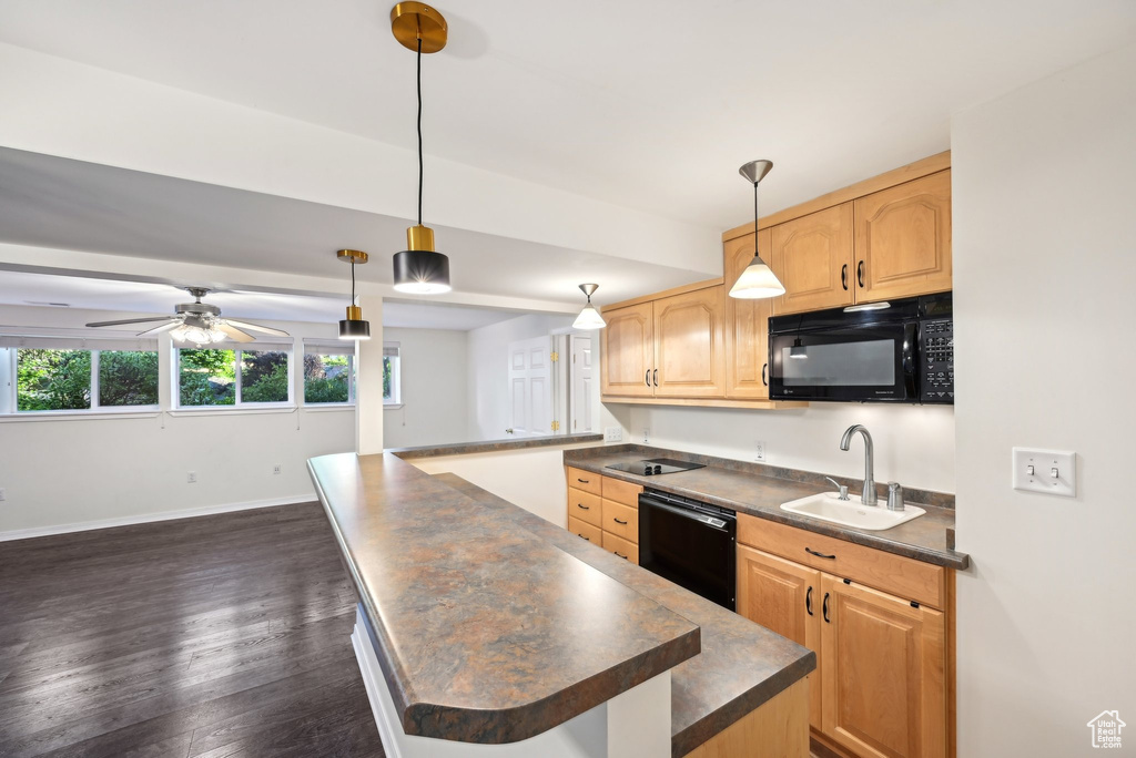 Kitchen featuring black appliances, a sink, a center island, and dark countertops