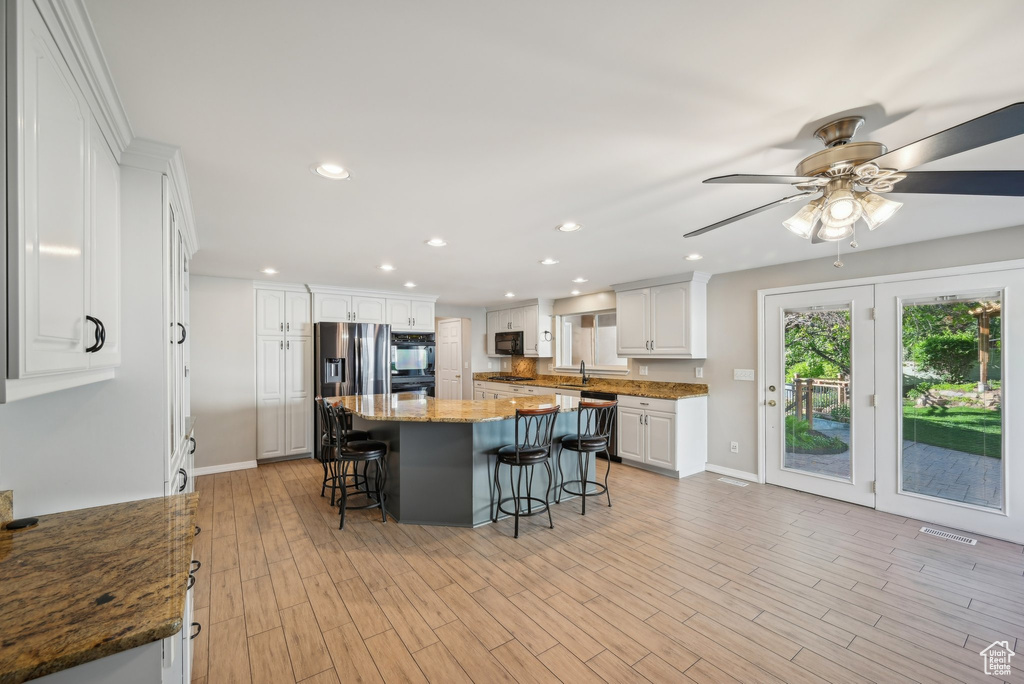 Kitchen featuring a kitchen breakfast bar, a sink, white cabinetry, a center island, and recessed lighting