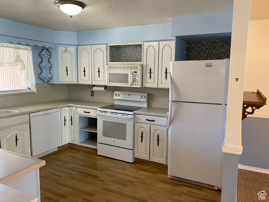Kitchen featuring light countertops, white cabinetry, white appliances, and wood finished floors