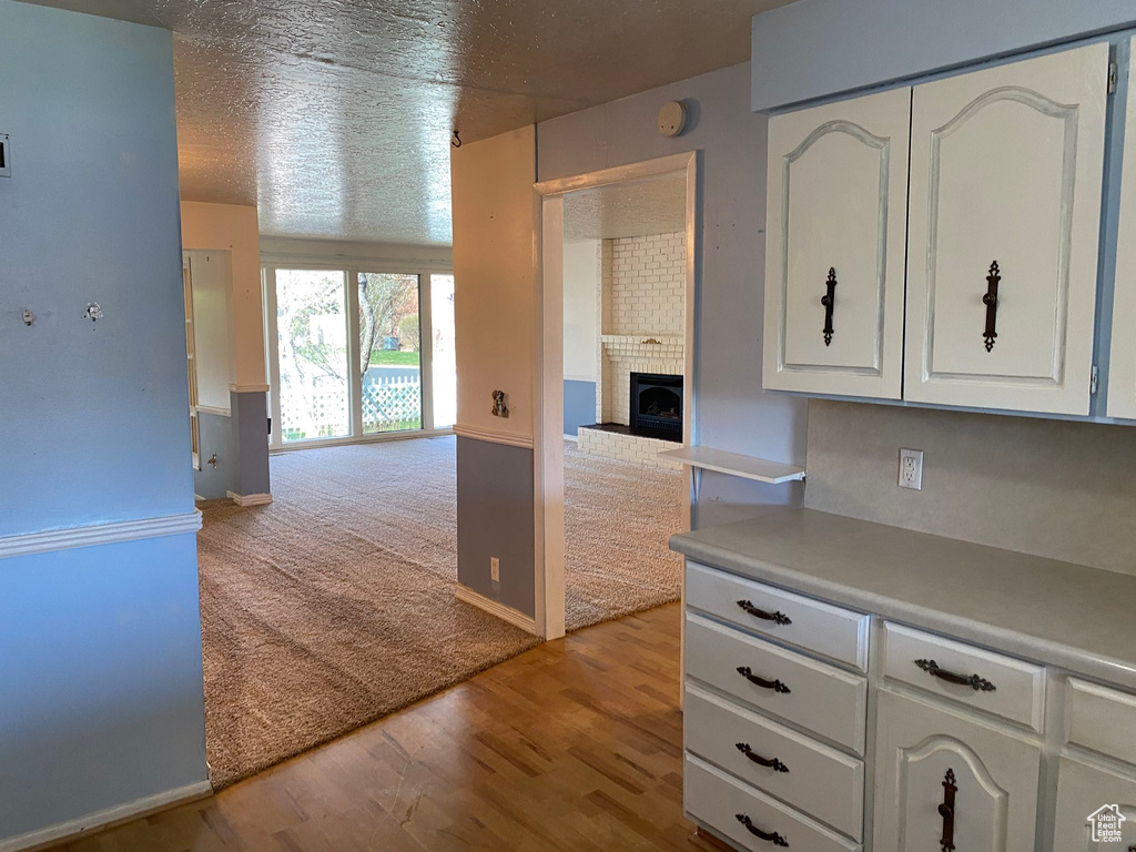 Kitchen with a fireplace, open floor plan, a textured ceiling, light countertops, and white cabinets