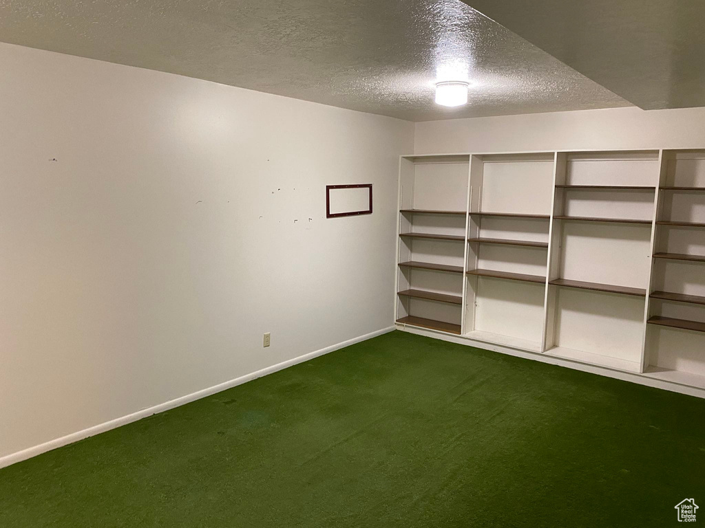 Basement with carpet flooring, a textured ceiling, and baseboards