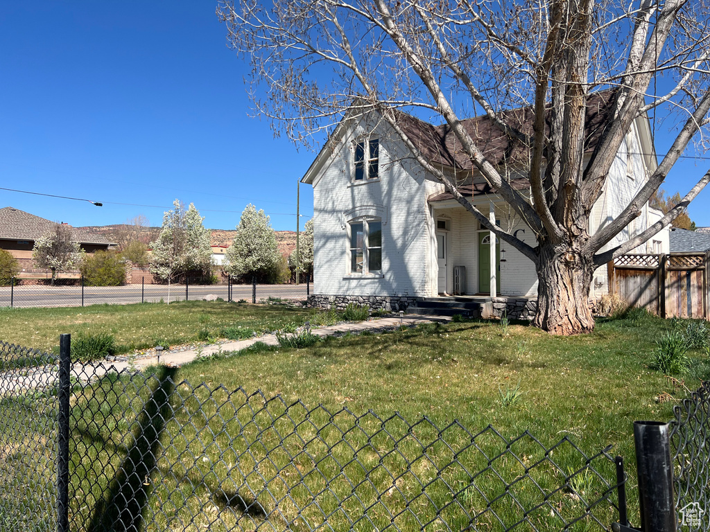 Exterior space featuring brick siding, fence, and a lawn