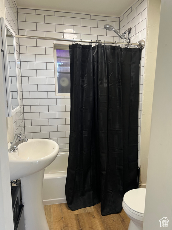 Full bathroom featuring shower / bath combo with shower curtain, toilet, and wood finished floors