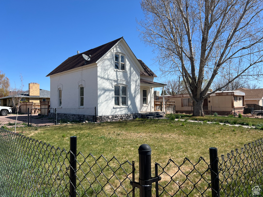 View of home\\\'s exterior featuring a yard, brick siding, fence, and a gate