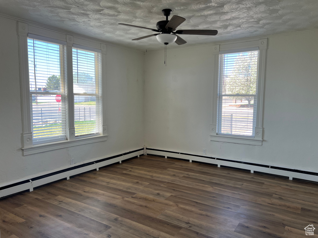 Spare room featuring wood finished floors, a ceiling fan, and a healthy amount of sunlight