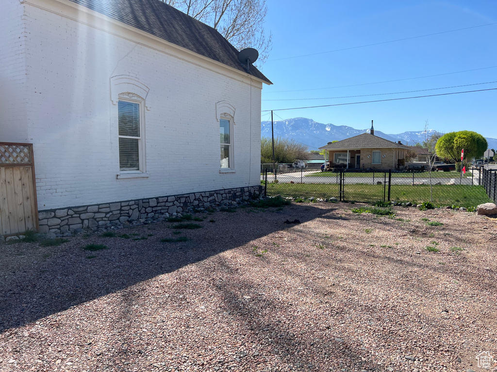 View of home\\\'s exterior with brick siding, a mountain view, and fence