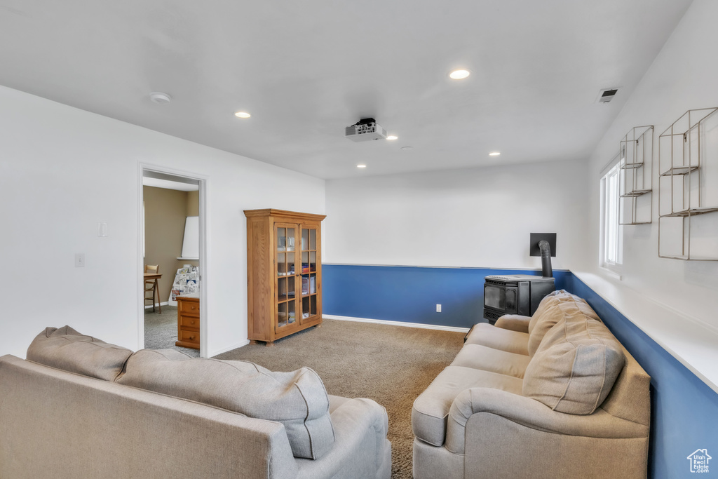 Living room with a wood stove, recessed lighting, carpet, and baseboards