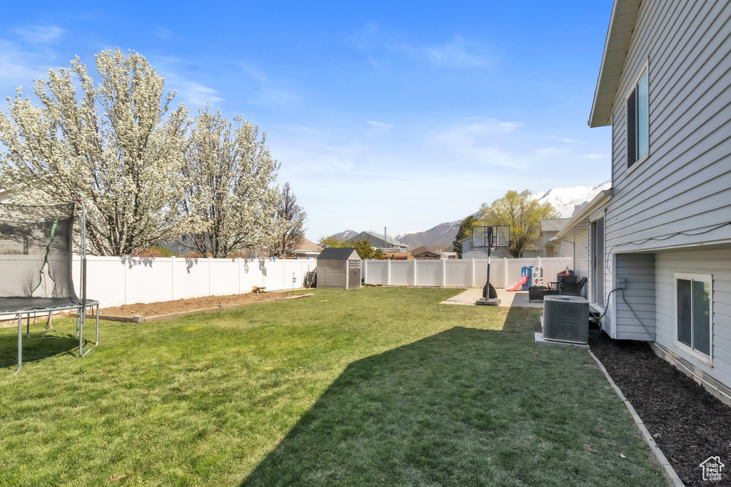 View of yard with an outbuilding, cooling unit, a fenced backyard, a patio, and a trampoline