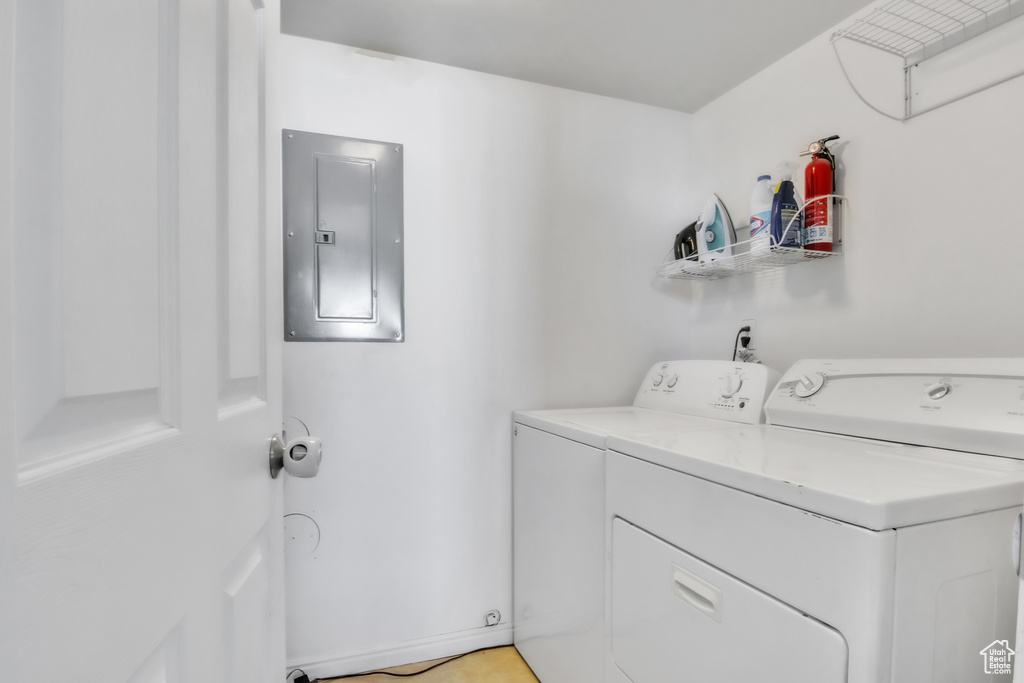 Laundry room with electric panel, laundry area, and washer and clothes dryer