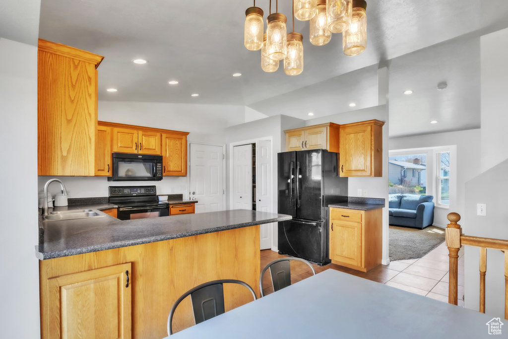 Kitchen with light tile patterned floors, a sink, dark countertops, a peninsula, and black appliances