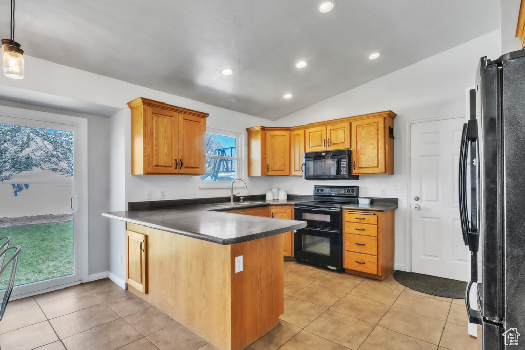 Kitchen with light tile patterned floors, a peninsula, black appliances, a sink, and dark countertops