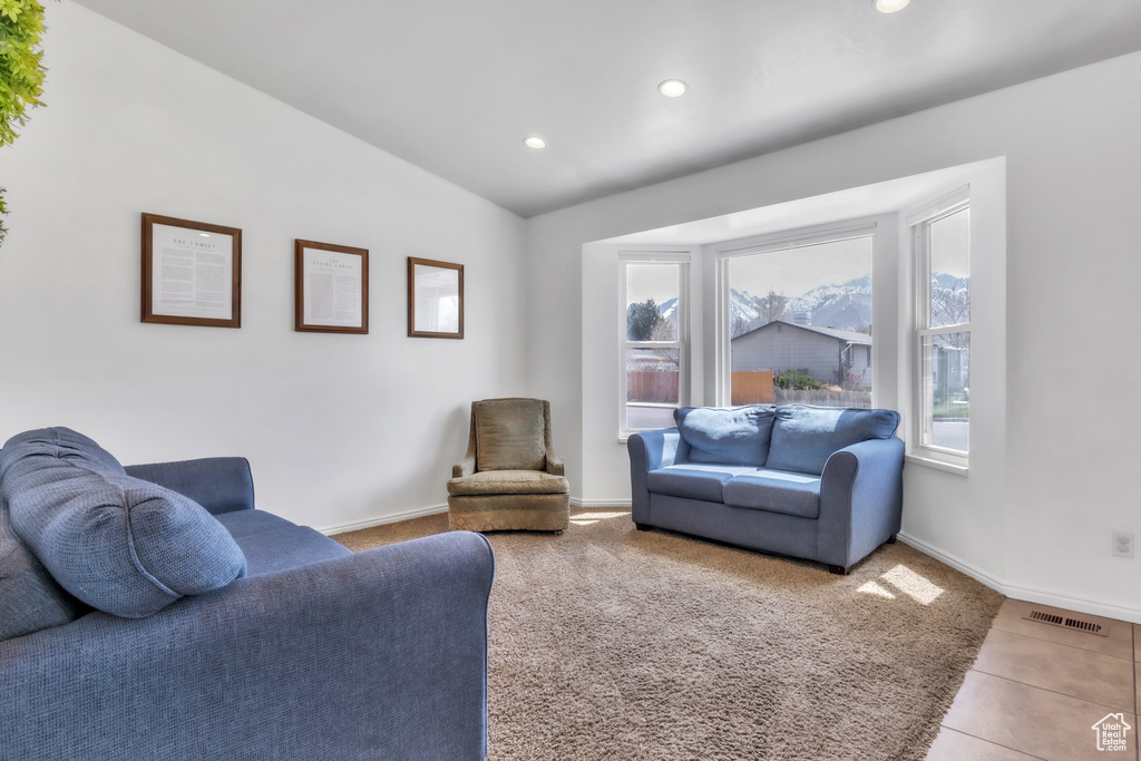 Living area featuring visible vents, recessed lighting, lofted ceiling, tile patterned floors, and baseboards