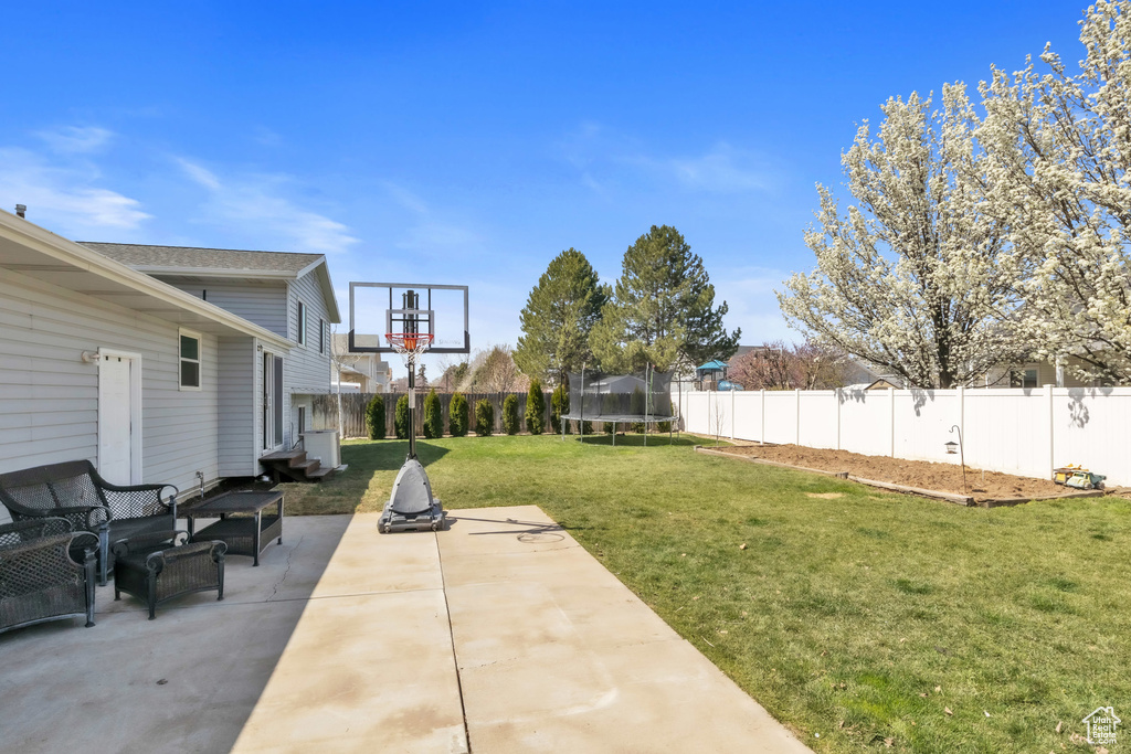 View of yard featuring a patio, a trampoline, and a fenced backyard