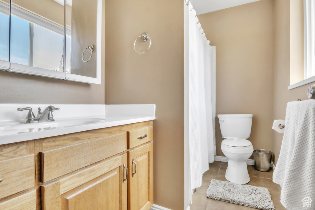 Bathroom featuring baseboards, a shower with curtain, toilet, vanity, and tile patterned floors