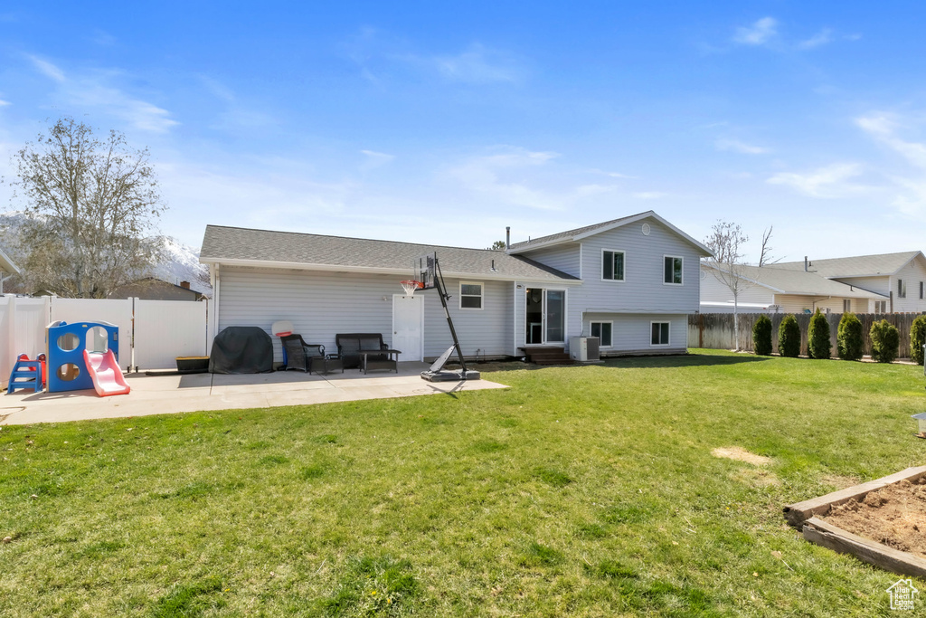 Back of house featuring a patio area, central AC unit, a fenced backyard, and a lawn