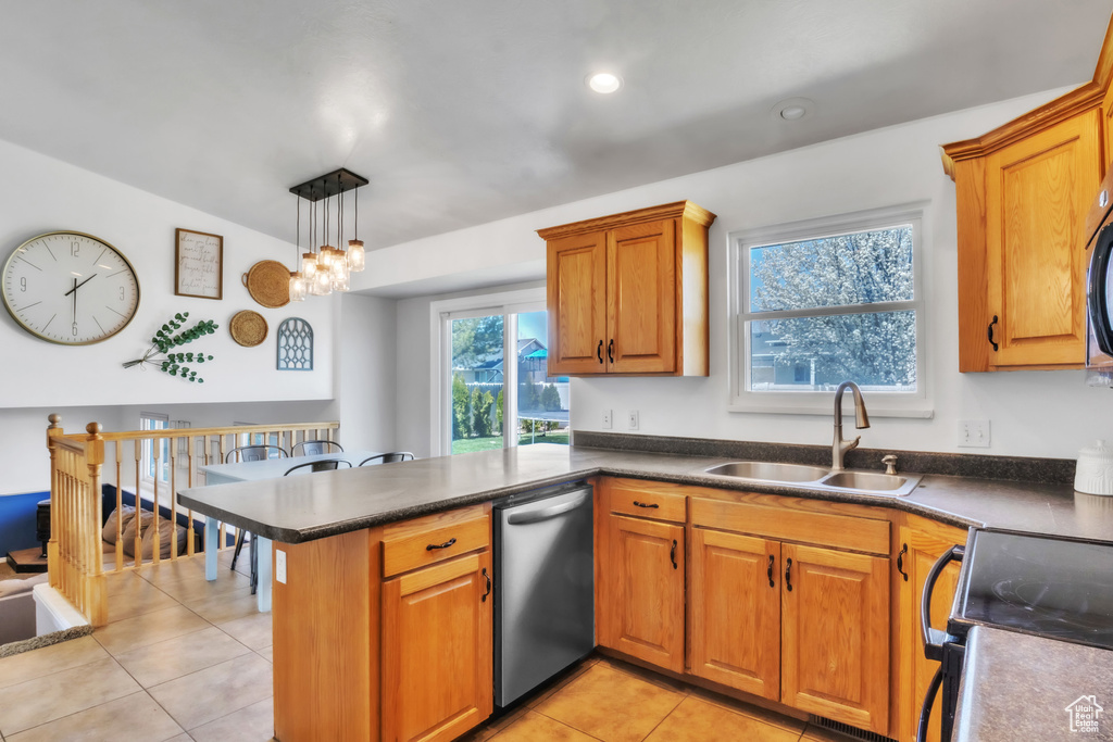 Kitchen featuring brown cabinetry, a peninsula, a sink, and appliances with stainless steel finishes