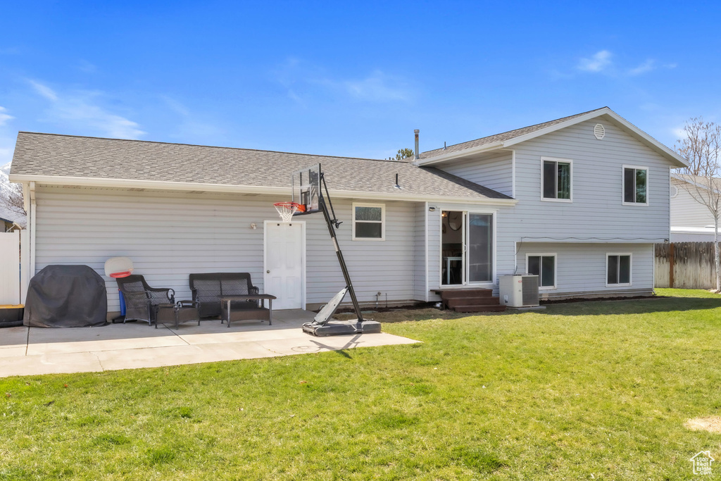 Rear view of property with a lawn, a patio, entry steps, fence, and a shingled roof