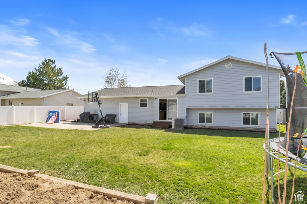 Back of property with a patio area, fence, a trampoline, and a yard