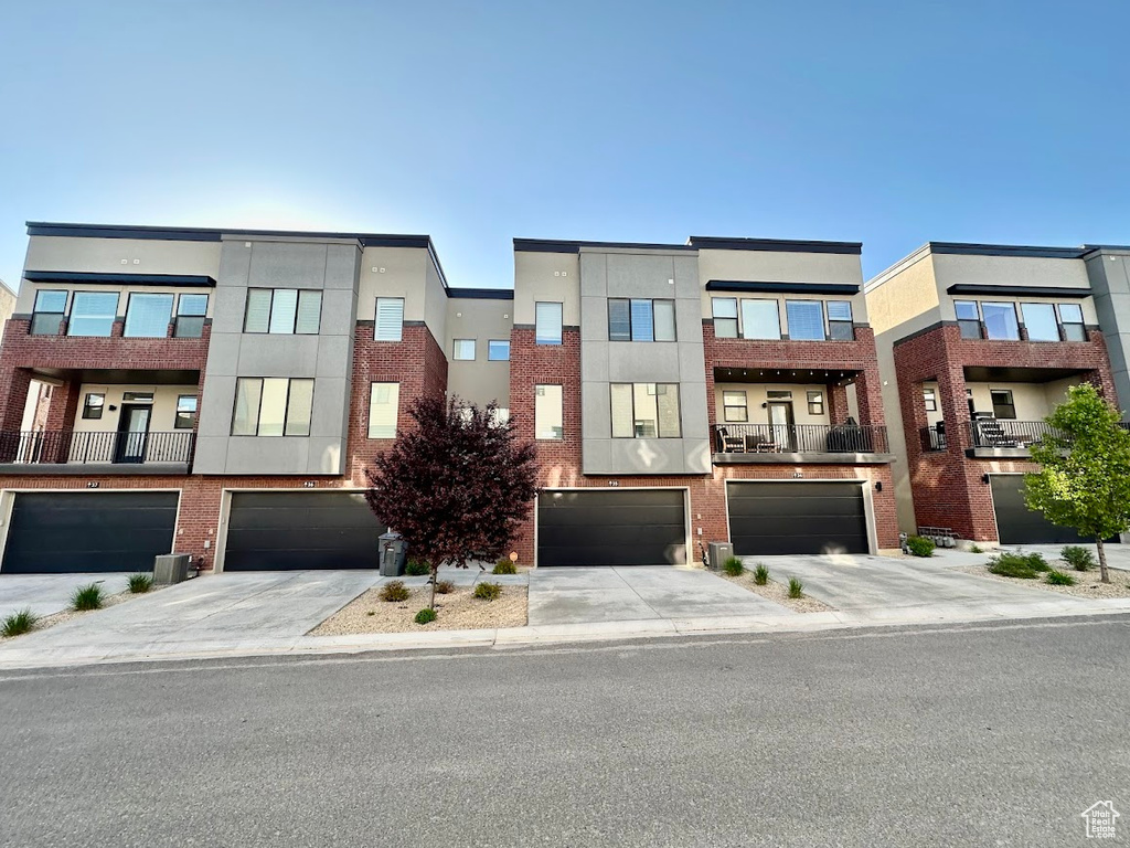 View of front of home with stucco siding, driveway, brick siding, and a garage