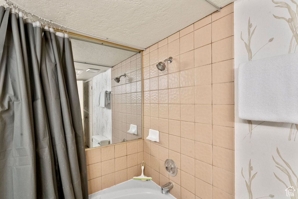 Full bathroom with a textured ceiling and shower / bath combo
