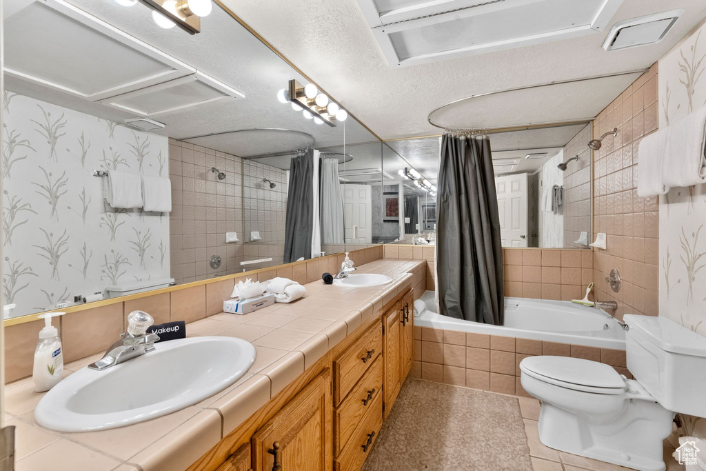 Full bathroom featuring a sink, tiled shower / bath, tile patterned floors, and toilet