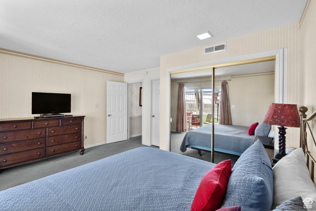 Carpeted bedroom with visible vents, a closet, baseboards, wallpapered walls, and a textured ceiling