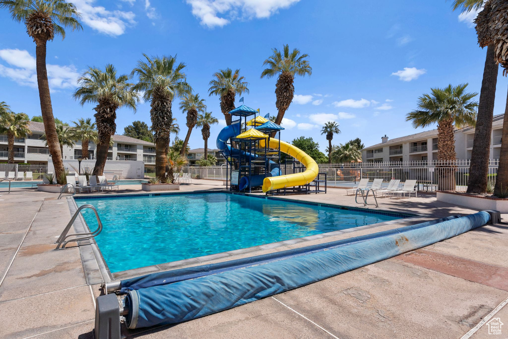 Community pool featuring fence, a water slide, a patio, and playground community
