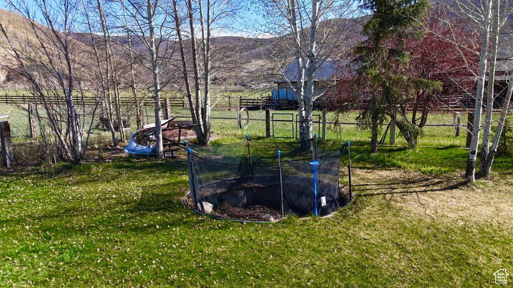 View of yard with a trampoline, a mountain view, and fence